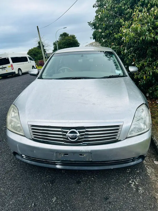 Silver Nissan Teana sedan parked on a Nelson street, ready for collection by Cash For Cars Nelson