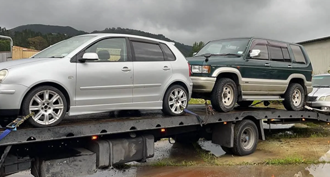 Tow truck carrying two scrap cars for removal in Nelson